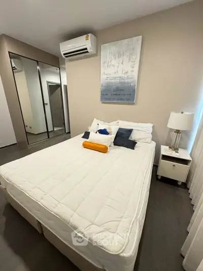 Modern bedroom with stylish decor and mirrored wardrobe in a cozy apartment.