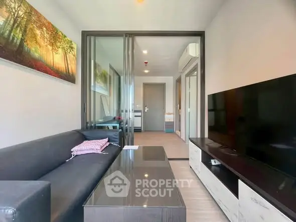 Modern living room with sleek furniture and large TV, featuring a stylish open layout and contemporary decor.