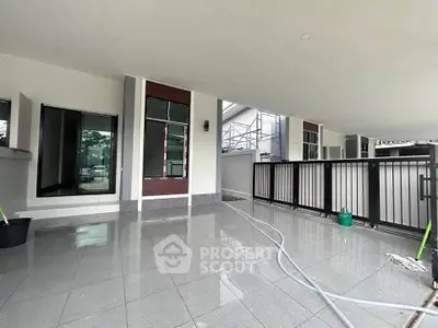 Spacious covered outdoor area with tiled flooring and modern railing, perfect for relaxation.