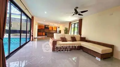 Spacious living room with pool view and modern open kitchen layout.