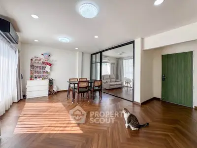 Spacious living room with wooden flooring and glass partition, featuring a cozy dining area.