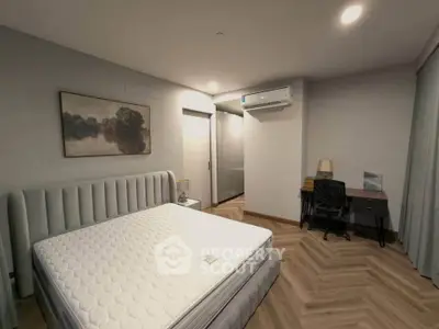 Spacious bedroom with modern decor and natural lighting, featuring a comfortable bed and stylish desk area.