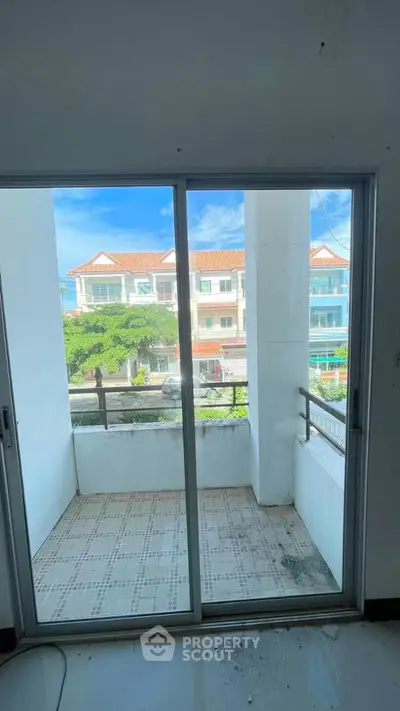 Charming balcony view from modern apartment with sliding glass doors and scenic neighborhood.