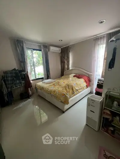 Spacious bedroom with natural light and modern decor, featuring a comfortable bed and stylish furnishings.