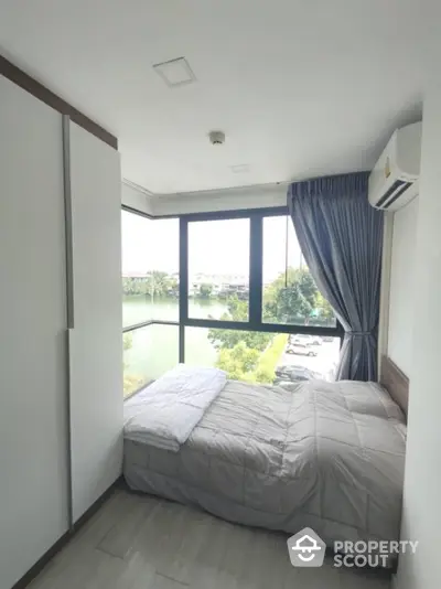 Modern bedroom with large windows offering stunning river view in high-rise apartment.