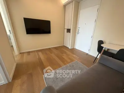 Modern living room with wall-mounted TV and cozy seating area in stylish apartment.