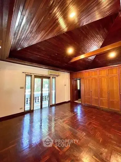 Spacious wooden interior with high ceiling and balcony access in luxury home.