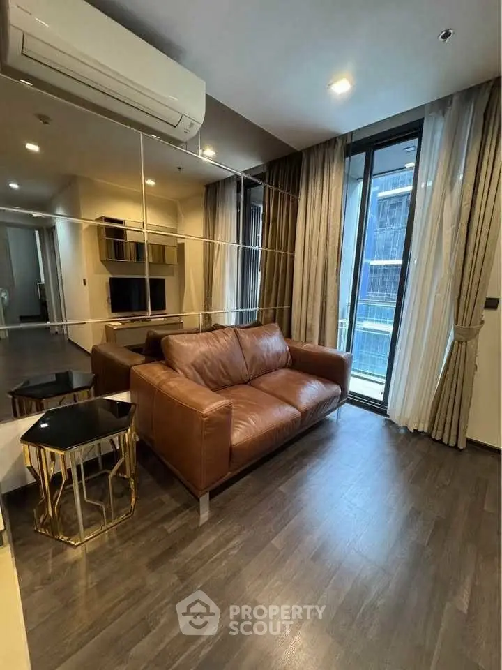 Modern living room with leather sofa and mirrored wall in high-rise apartment.