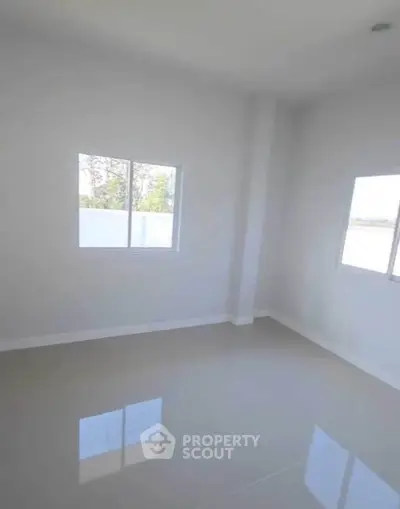 Bright empty room with large windows and glossy tiled floor.