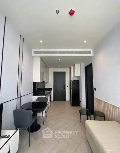 Modern living room with sleek furniture and open kitchen layout in a stylish apartment.