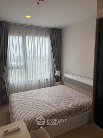 Cozy bedroom with large window and modern furnishings in a stylish apartment.