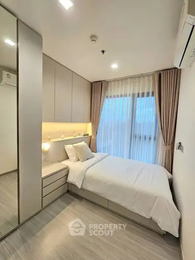 Modern bedroom with sleek design, large window, and cozy ambiance in a contemporary apartment.