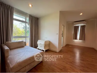 Spacious living room with large window and elegant chaise lounge