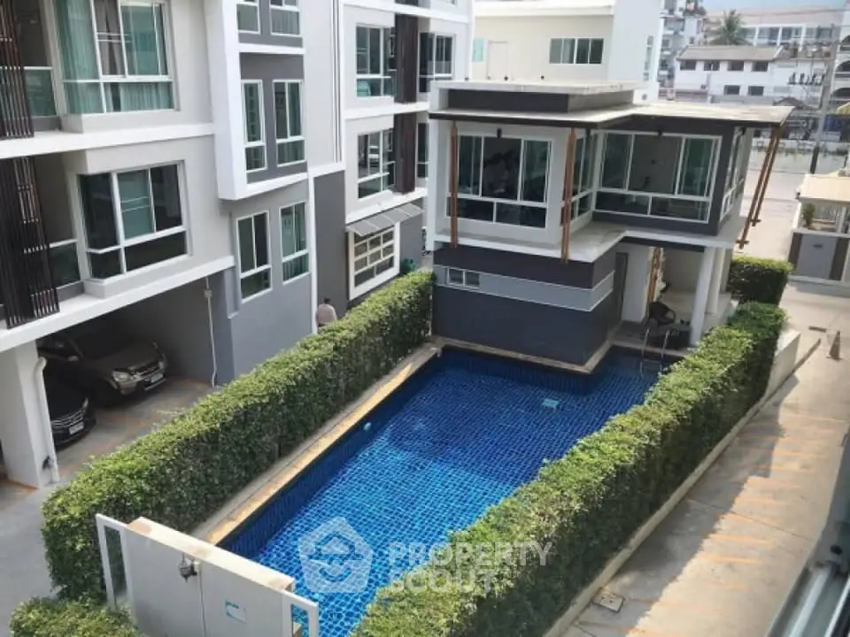 Modern apartment complex with a pristine swimming pool and lush greenery.