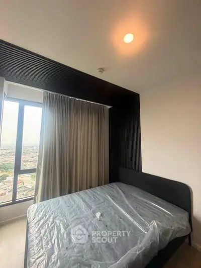 Modern bedroom with large window offering city view, featuring sleek black accent wall and cozy bed.