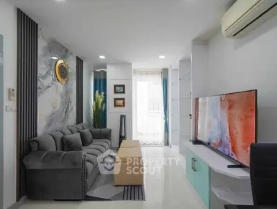 Modern living room with stylish decor, large TV, and comfortable seating in a bright apartment.