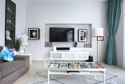 Modern living room with sleek decor, wall-mounted TV, and stylish furniture in a bright, airy space.
