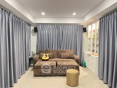Cozy living room with plush sofa and guitar, elegant curtains and display cabinet.