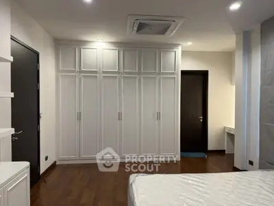 Spacious bedroom with elegant built-in wardrobe and modern ceiling fan.