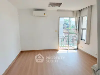 Spacious empty room with wooden flooring and balcony access, perfect for customization.