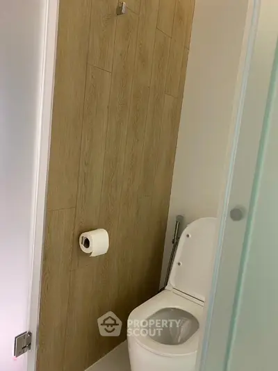 Modern bathroom with wooden accent wall and sleek toilet design