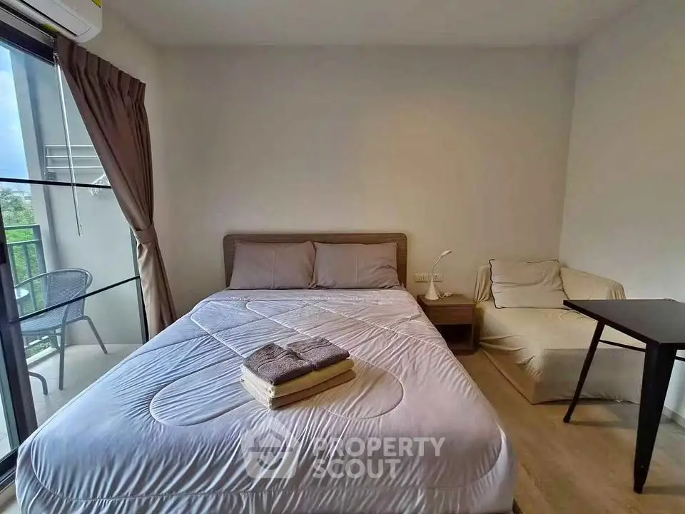 Cozy bedroom with large window and balcony access, featuring a comfortable bed and modern decor.