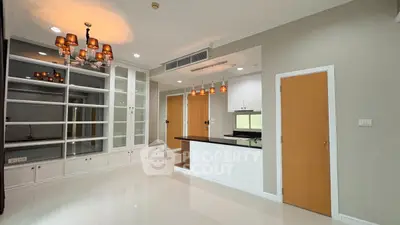 Spacious modern living room with elegant lighting and open kitchen layout.
