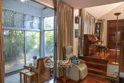 Charming living room with elevated piano area and large windows overlooking lush greenery.