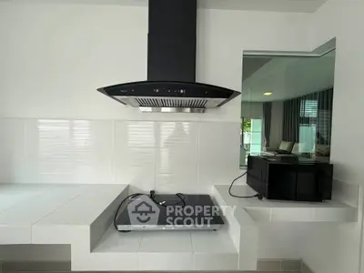 Modern kitchen with sleek black stove and microwave, featuring minimalist white tile design.