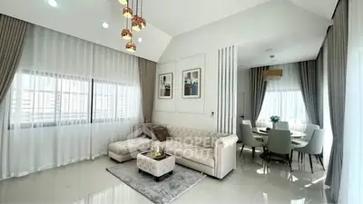Luxurious living room with elegant decor and dining area, featuring high ceilings and modern lighting.