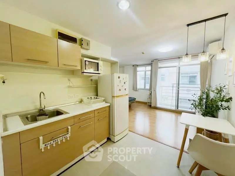 Modern open-layout kitchen with dining area and bright living space, featuring stylish lighting and large windows.