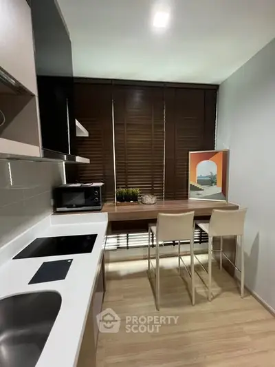 Modern kitchen with sleek design, featuring induction cooktop and cozy dining area with stylish decor.