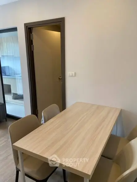 Modern dining area with wooden table and chairs in a cozy apartment setting.