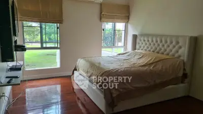 Spacious bedroom with large windows and elegant bed, offering serene garden views.