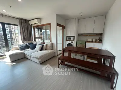 Modern living room with open kitchen, featuring stylish furniture and natural light.