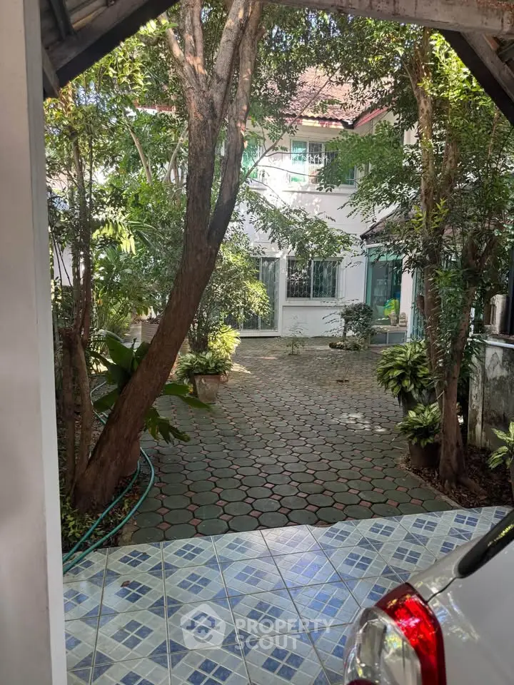 Charming house with lush garden and tiled driveway, perfect for serene living.