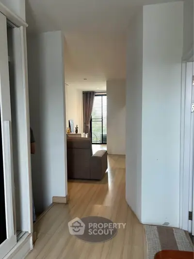 Spacious modern apartment hallway leading to a cozy living room with natural light.