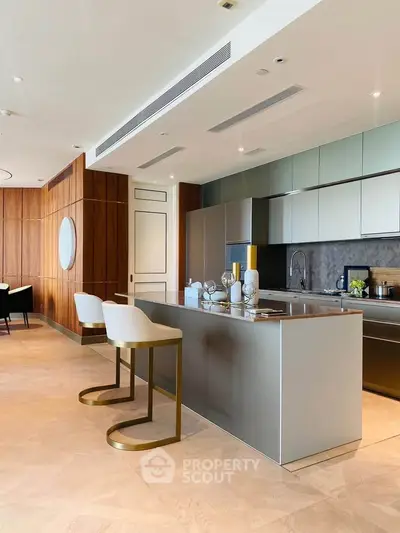 Luxurious modern kitchen with sleek island and stylish bar stools in open layout design.