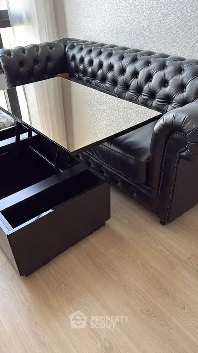 Luxurious black leather sofa with sleek glass coffee table in modern living room.