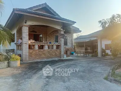 Charming single-story brick house with spacious driveway and lush greenery, perfect for serene living.