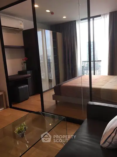 Modern bedroom with glass partition and city view, featuring sleek furniture and natural light.