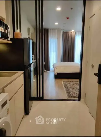 Modern studio apartment with sleek kitchen and cozy bedroom, featuring elegant decor and ample natural light.