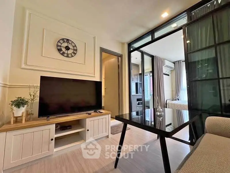 Modern living room with stylish decor and glass partition leading to bedroom