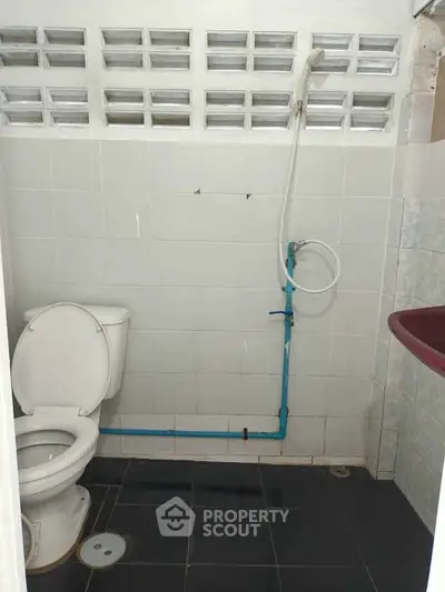 Compact bathroom with white tiles and basic fixtures, ideal for small spaces.