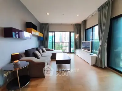 Spacious modern living room with large windows and stylish furniture in a high-rise apartment.