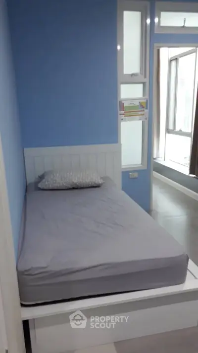 Cozy bedroom with blue walls and large window for natural light
