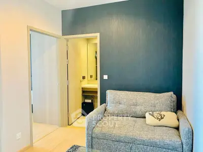 Cozy living room with modern sofa and open door to bathroom, featuring stylish decor.