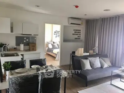 Modern open-plan living room with dining area and view into cozy bedroom, featuring stylish decor and natural light.