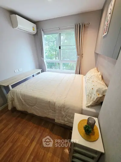 Cozy bedroom with large window and wooden flooring, featuring a comfortable bed and modern decor.