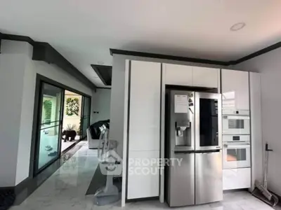 Modern kitchen with sleek appliances and open layout leading to living area.